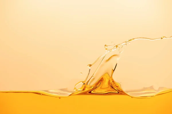 Liquido giallo brillante con spruzzi e onda isolata su giallo — Foto stock