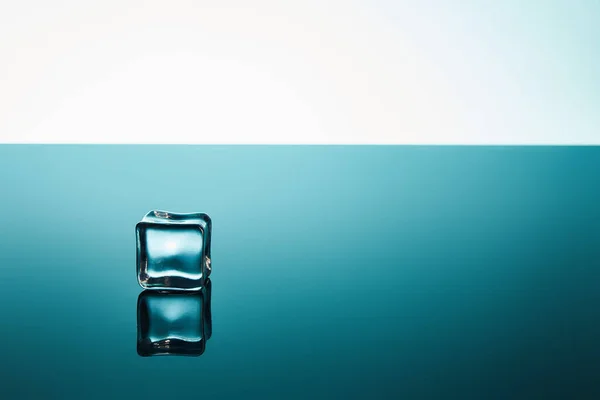 Glaçon transparent sur fond émeraude et blanc — Photo de stock