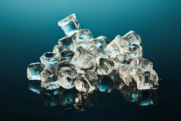 Pile de glaçons transparents sur fond émeraude — Photo de stock