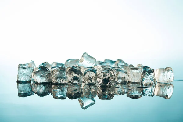 Stack of transparent ice cubes on emerald and white background — Stock Photo