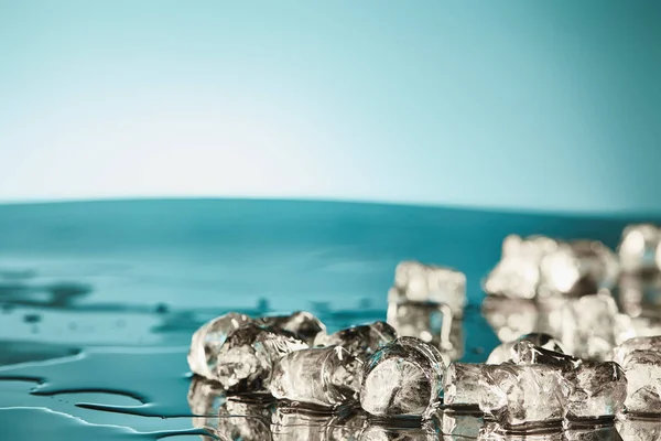 Cubos de hielo de fusión transparente sobre fondo esmeralda y blanco - foto de stock