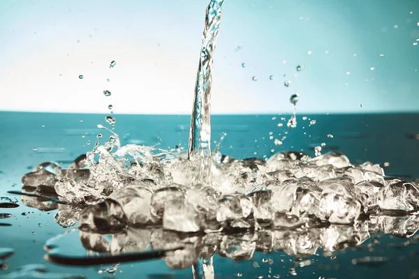 Cubos de hielo de fusión transparentes con agua de vertido sobre fondo esmeralda y blanco - foto de stock