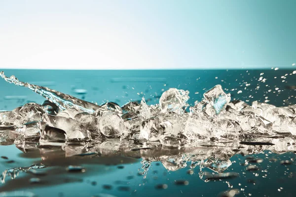 Холодное таяние кубиков льда с брызгами воды на изумрудном и белом фоне — стоковое фото