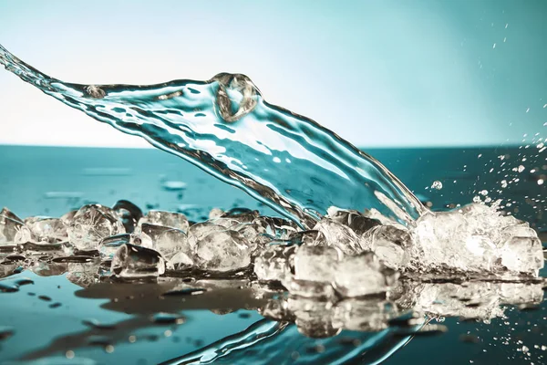 Cubos de gelo transparentes e respingo de água no fundo esmeralda e branco — Fotografia de Stock