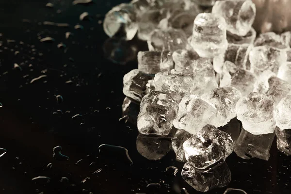 Stack of transparent cool ice cubes on black background with water drops — Stock Photo