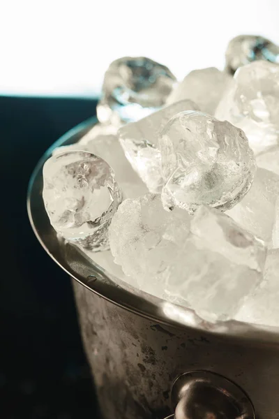 Close up view of transparent ice cubes in metal bucket on emerald and white background — Stock Photo