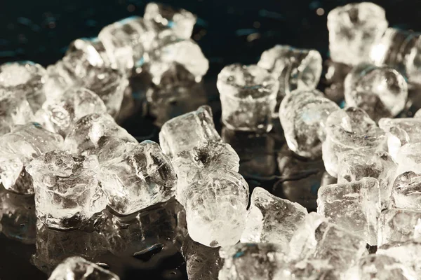 Cubos de gelo frios transparentes no fundo preto com gotas de água — Fotografia de Stock
