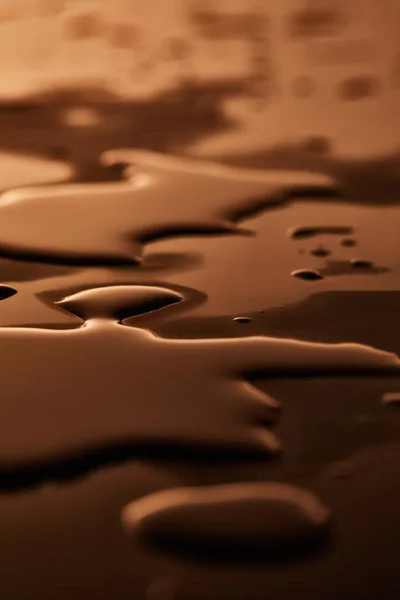 Charcos de agua y gotas en la superficie marrón - foto de stock