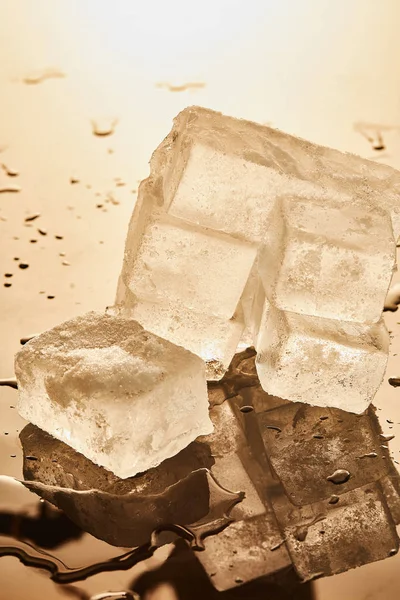 Stack of ice cubes with puddles on illuminated background — Stock Photo