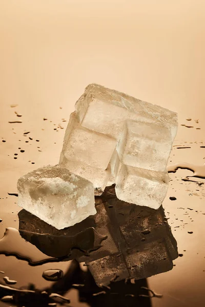 Stack of transparent melting ice cubes on brown background — Stock Photo