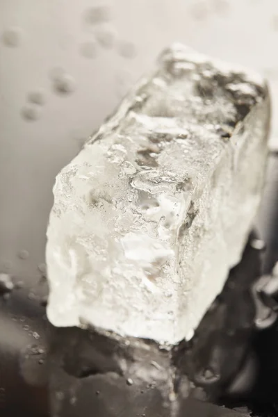 Close up view of transparent wet textured ice cube on black background — Stock Photo