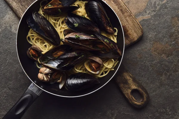 Vista superior de la deliciosa pasta con mariscos sobre tabla de cortar de madera sobre fondo gris envejecido - foto de stock