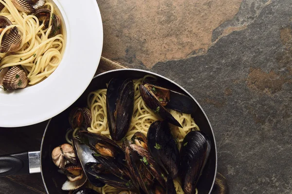 Vista dall'alto di deliziose paste con molluschi e cozze su tagliere in legno su fondo grigio intemperie — Foto stock