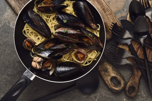 Draufsicht auf köstliche Pasta mit Weichtieren und Miesmuscheln in der Pfanne auf verwittertem grauem Hintergrund — Stockfoto