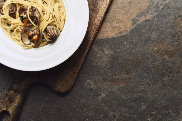 Vista dall'alto di deliziosa pasta con molluschi su tagliere invecchiato in legno su sfondo intemperie con spazio copia — Foto stock