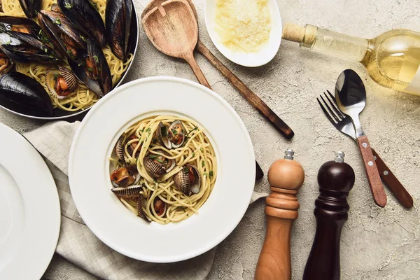 Vue de dessus de délicieuses pâtes aux fruits de mer servies avec du fromage râpé et du vin blanc — Photo de stock