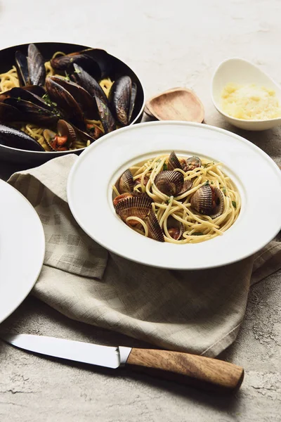 Foco selectivo de deliciosa pasta con mariscos y queso rallado en la servilleta cerca del cuchillo - foto de stock