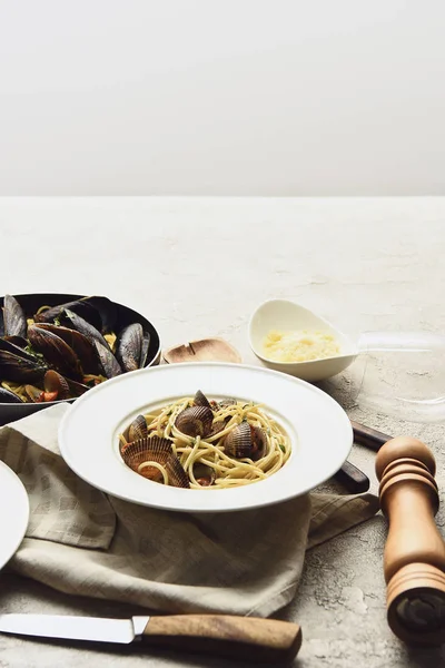 Köstliche Pasta mit Meeresfrüchten und geriebenem Käse auf Serviette neben Messer isoliert auf grau — Stockfoto