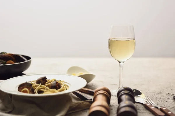Deliciosa pasta con mariscos servida con vino blanco aislado en gris - foto de stock