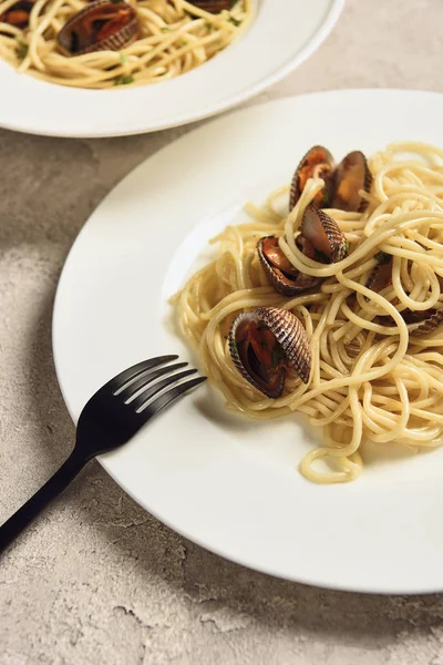 Vue rapprochée de délicieuses pâtes aux fruits de mer servies dans deux assiettes blanches avec fourchette — Photo de stock