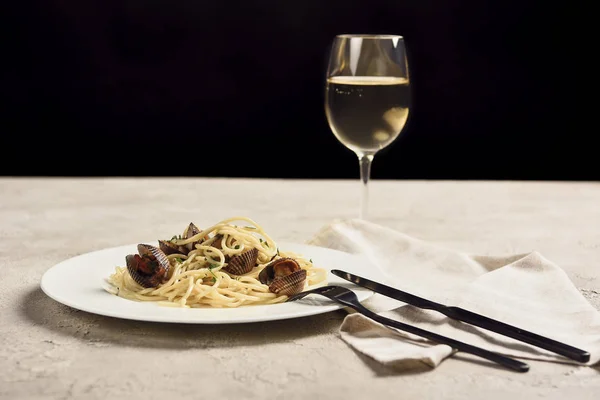 Deliciosos espaguetis italianos con mariscos servidos con vino blanco aislado en negro - foto de stock
