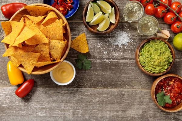 Vue du dessus des nachos mexicains servis avec guacamole, sauce au fromage et salsa sur une table en bois altérée — Photo de stock