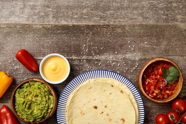 Vista superior da tortilha mexicana com guacamole, molho de queijo e salsa na mesa de madeira intemperizada — Fotografia de Stock
