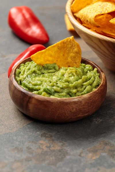 Close up view of Mexican nachos with guacamole and chili peppers on stone table — Stock Photo