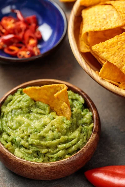 Selective focus of Mexican nachos with guacamole and chili peppers on stone table — Stock Photo