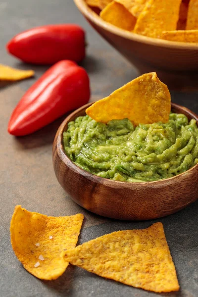 Close up view of crispy Mexican nachos with guacamole and chili peppers on stone table — Stock Photo