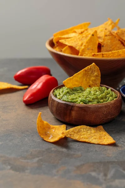 Nachos mexicanos con guacamole y chiles sobre mesa de piedra aislados en gris - foto de stock