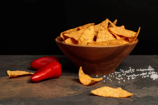 Nachos mexicanos salgados com pimentas vermelhas na mesa de pedra isolada em preto — Fotografia de Stock