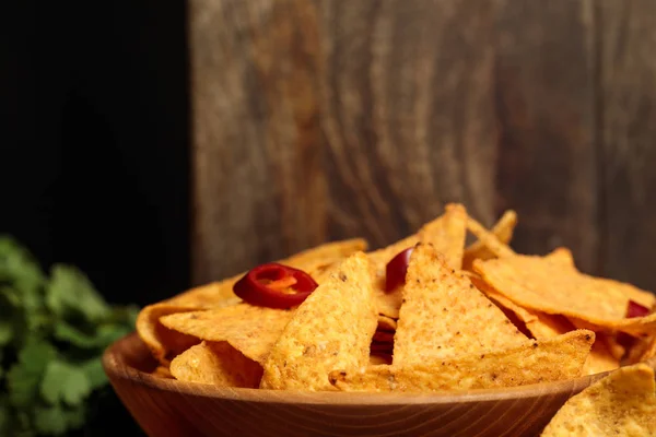 Close up view of Mexican nachos with chili peppers near wooden cutting boards isolated on black — Stock Photo