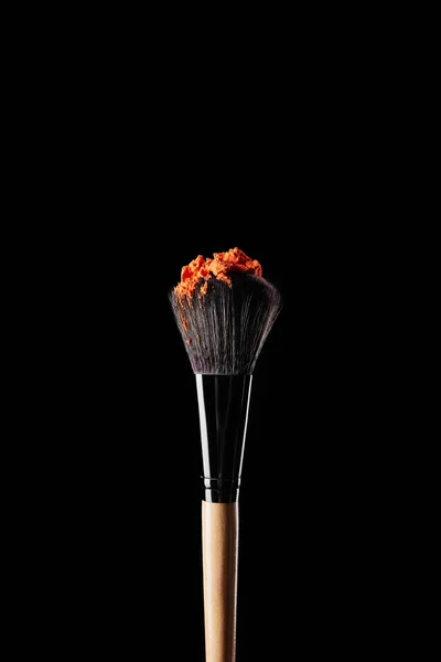 Cepillo cosmético con polvo de naranja aislado en negro - foto de stock