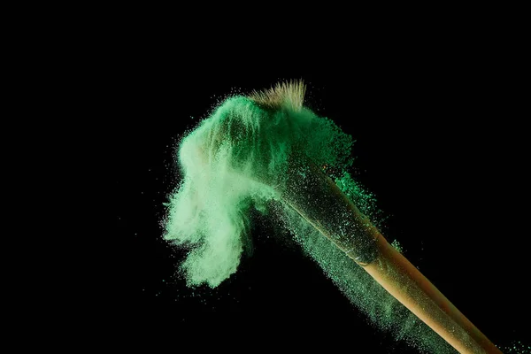 Cosmetic brush with colorful green powder on black background — Stock Photo