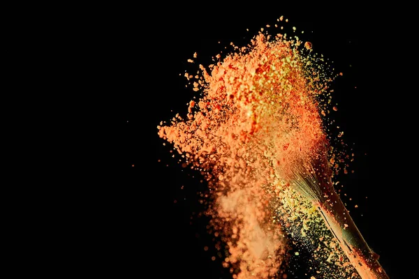 Escova cosmética com explosão de tinta laranja no fundo preto com espaço de cópia — Fotografia de Stock