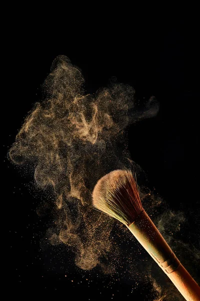 Cosmetic brush with colorful light powder on black background — Stock Photo