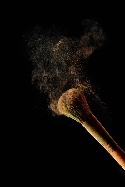 Cosmetic brush with light powder on black background — Stock Photo