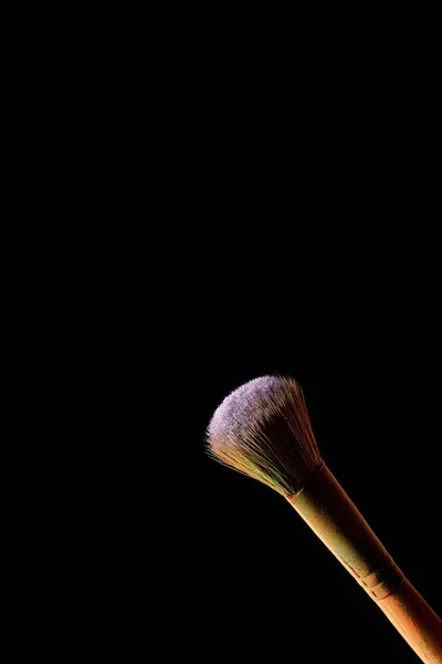 Cosmetic brush with colorful violet powder isolated on black — Stock Photo