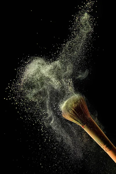 Cosmetic brush with yellow colorful powder paint on black background — Stock Photo