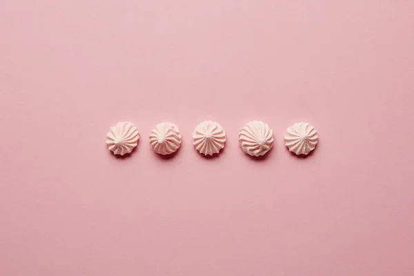 Flat lay with pink meringues in horizontal row on pink background — Stock Photo