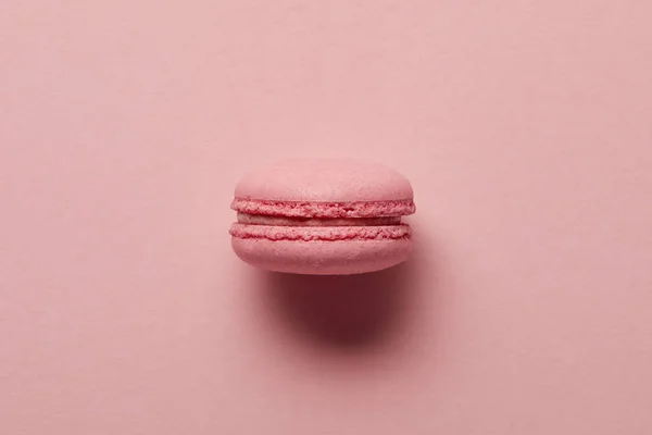 Pink french macaroon in center on pink background — Stock Photo