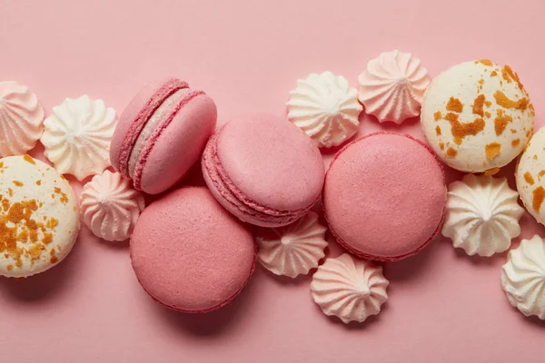 Macarrones rosados y blancos sabrosos con merengues rosados y blancos sobre fondo rosado - foto de stock