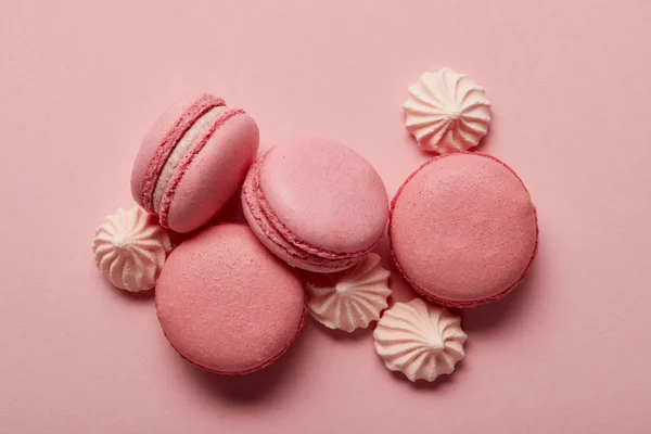 Macarrones rosados con merengues rosados sobre fondo rosa - foto de stock