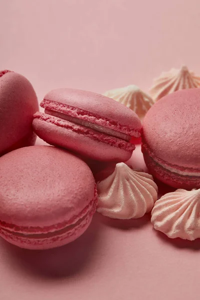 Macarrones rosados con merengues pequeños sobre fondo rosa - foto de stock