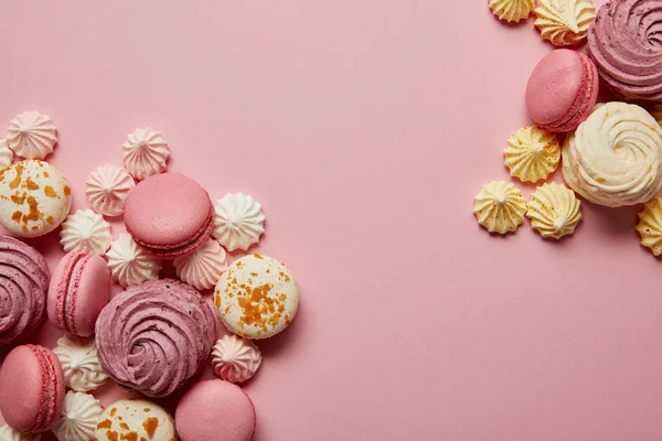 Смачні солодкі макаруни та барвисті обертання на рожевому фоні — стокове фото