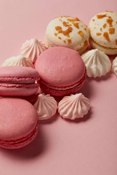 Sabrosos macarrones franceses con merengues sobre fondo rosa - foto de stock