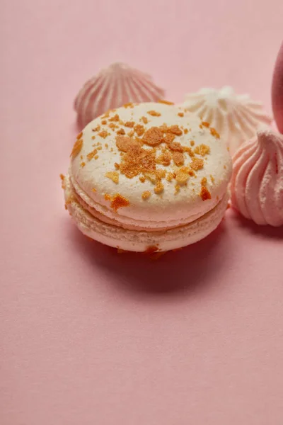 White macaroon with yellow pieces and meringues on pink background — Stock Photo