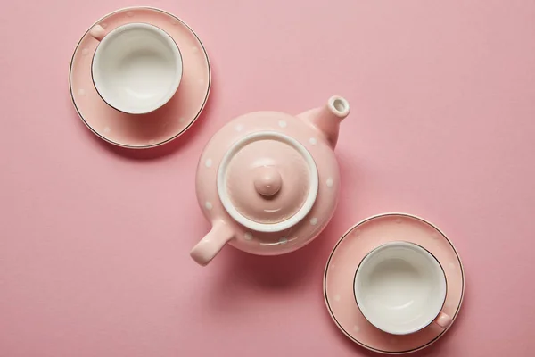 Théière à pointillés rose pastel et tasses avec soucoupes sur fond rose — Photo de stock