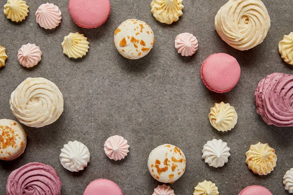 Vista superior de macarrones rosados y blancos con merengues sobre fondo gris - foto de stock